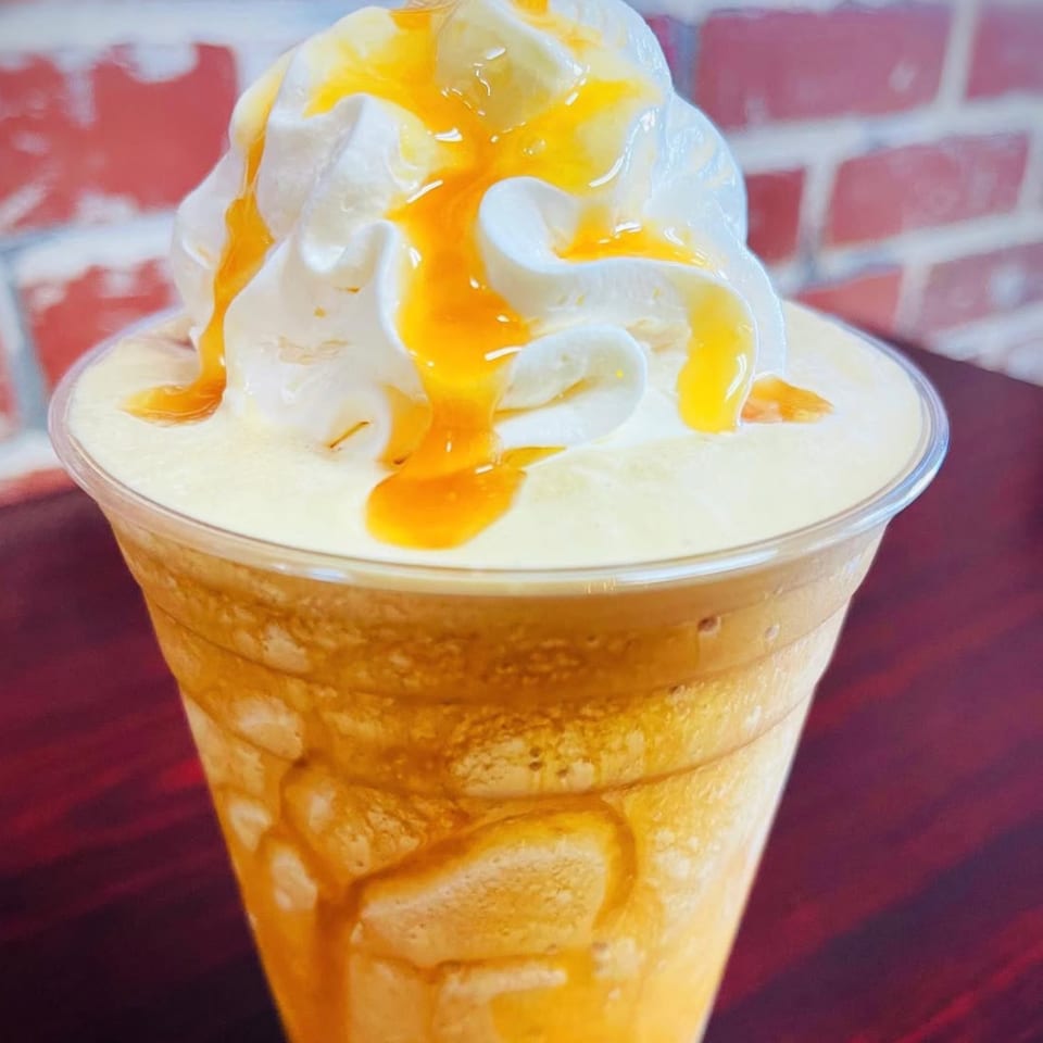 Sweet Desert Cafe's caramel frappe with whipped cream and caramel drizzle in a clear cup.