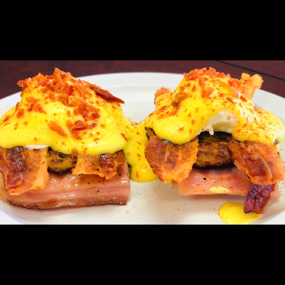 Two Sweet Desert Cafe breakfast dishes with bacon, eggs benedict, and hollandaise sauce.