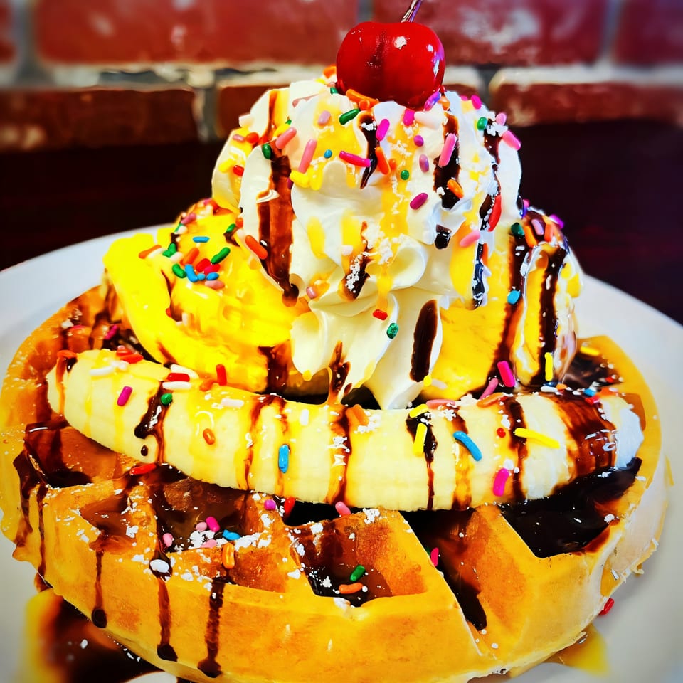 Sweet Desert Cafe's waffle topped with bananas, ice cream, whipped cream, sprinkles, chocolate, and a cherry.