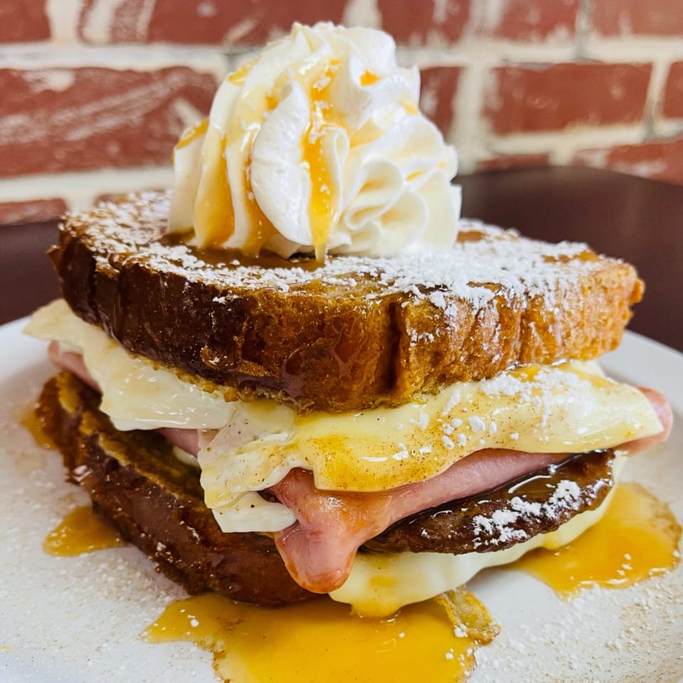 Sweet Desert Cafe's French toast sandwich with ham, egg, cheese, whipped cream, and syrup.